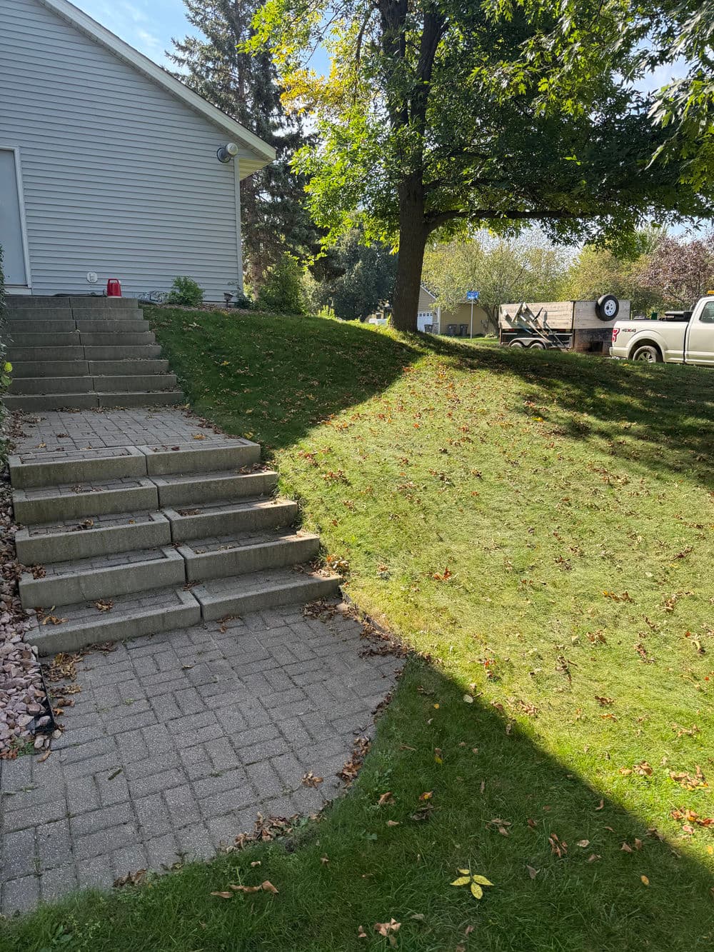 Staircase leading to a grassy area with autumn leaves and residential backyard scenery.
